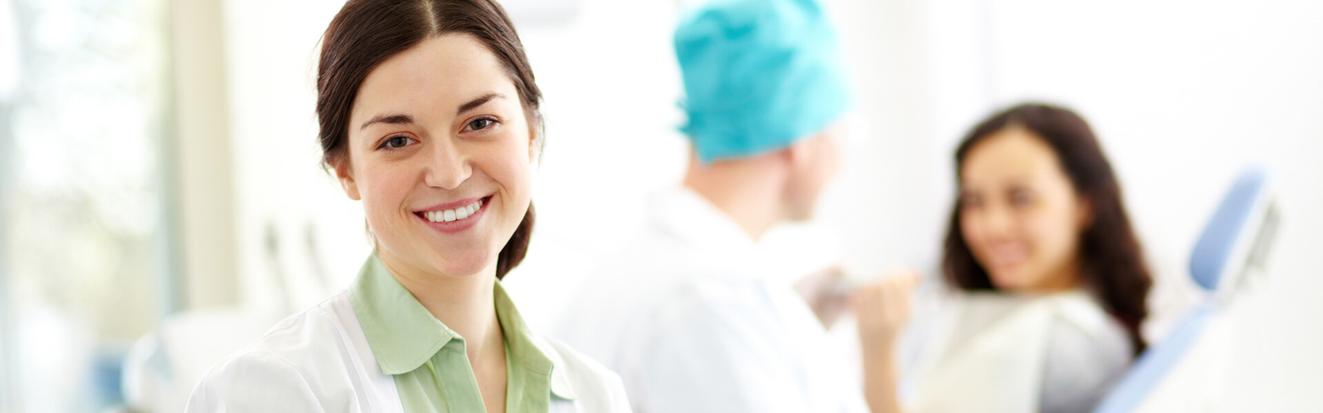Dental assistant smiling at the camera in a blurred background