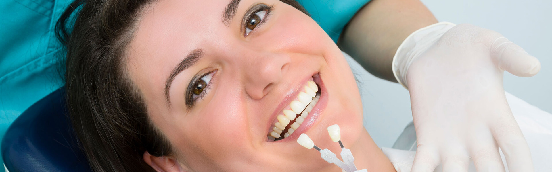 Comparing tooth colored fillings while a female patient is smiling at the camera